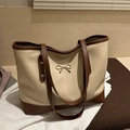 Bolso tote en contraste beige y marrón con hebilla de lazo dorado en una estancia - Caqui