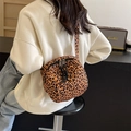 Vrouw draagt een crossbodytas met luipaardprint en dubbele rits in een casual buitenomgeving - Luipaard Bruin