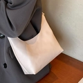 Minimalist beige PU leather tote bag with lychee texture held by a model in a gray suit - Off White