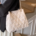Borsa tote beige trapuntata con catena dorata portata a spalla da una modella - Bianco