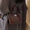 Minimalist dark brown glossy leather bucket bag with silver twist lock and crossbody strap - Coffee