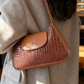 Brown crocodile embossed underarm bag with silver bow accent on model wearing tweed coat - Brown