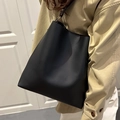 Minimalistische schwarze Leder-Eimertasche getragen mit einem khakifarbenen Trenchcoat - Schwarz