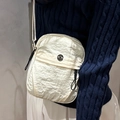 Sac bandoulière chic en nylon beige avec logo en métal sur un mannequin femme - Blanc