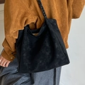 Bolso tote grande de ante negro con correa de hombro trenzada llevado por modelo - Negro