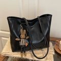 Large black faux leather tote bag with a woven rabbit pendant on a beige plush surface - With Rabbit Pendant / Black