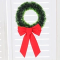 Grüner Weihnachtskranz mit roter Schleife und Schneeeffekt vor weißem Fensterhintergrund - Grüner Kranz