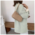 Minimalistische beige Schultertasche aus mattem Leder getragen von einem Modell im Innenraum - Khaki