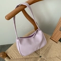 Chic lilac faux leather baguette shoulder bag hanging on a woven rattan chair - Purple