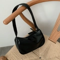 Minimalist black synthetic leather hobo shoulder bag with zipper in a natural setting - Black