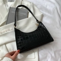 Elegante borsa sottobraccio nera motivo coccodrillo con zip dorata su sfondo blazer bianco - Nero