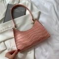 Pink baguette bag with crocodile texture and gold zipper in a stylish setting - Pink