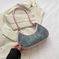 Bolso de hombro en denim con borde rosa y logo dorado colocado sobre un blazer beige - Rosa