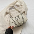 Bolso de hombro de lona beige minimalista con cadena plateada y tachuelas sobre un traje - Blanco