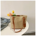 Dettaglio della borsa in paglia intrecciata con manici in pelle e ciondolo moda - Marrone