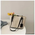 Dettaglio di una borsa tote in paglia con manici in pelle nera e targhetta fashion - Nero