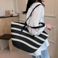 Bolso tote de paja tejida a rayas blancas y negras llevado por la modelo - Negro