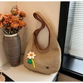 Beige Stroh-Hobo-Tasche mit braunem Lederbesatz und einer weißen Plüschblume-Deko - Blumenstil