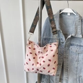 Pink corduroy tote bag with strawberry print and vintage woven strap shoulder view - Pink