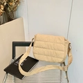 Chic quilted beige crossbody bag with wide strap on a modern chair in warm minimalist setting - Khaki