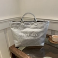 Detalle del bolso tote plateado metalizado con textura arrugada y estampado - Plateado