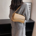 Brown leather shoulder bag with asymmetrical wave flap and gold hardware on female model - Yellow Brown