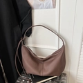 Detail of a brown lychee pattern leather crescent bag with a silver zipper on a suitcase - Brown