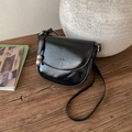 Detalle de bolso de silla negro brillante con logo grabado y colgante de maní metálico - Negro