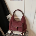 Dettaglio borsa tote bordeaux con cuciture a contrasto e tasca su una valigia metallica - Rosso