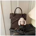 Détail d'un sac à dos vintage marron foncé avec un lapin en peluche blanc et boucle métal - Café avec Pendentif