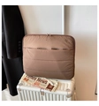 Business travel scene showing a brown quilted laptop sleeve on a striped suitcase - Coffee