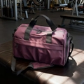 Dunkelrosa Reisetasche aus Segeltuch mit großem Fassungsvermögen auf einer Fitnessbank - Lila
