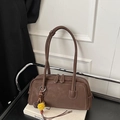 Close-up of brown pebbled leather bowling bag with white stitching and plush charms - With Charm / Brown