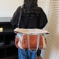 Beige and brick red large capacity travel bag worn by model in a casual indoor setting - Gray