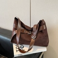 Dark brown suede tote bag with leather straps and silver buckle on a luxury sofa - Brown