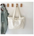 Detail of off-white canvas tote bag featuring functional side pockets and front drawstring - One Size / White