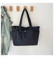 Detail of black multi-pocket tote bag with drawstring pocket hanging on a wall - One Size / Black