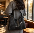 Large black woven leather tote bag with silver zippers shown on a model in a cafe - Black
