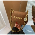 Detailed close-up of brown suede baguette bag with gold heart logo and chunky chain strap - Khaki