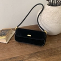 Detalle del bolso de hombro de ante negro con hebilla metálica dorada en mesa de madera - Negro