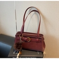 Detail der weinroten Kunstledertasche mit Retro-Goldschnalle und Pelzball-Anhänger - Weinrot Mit Anhänger