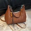 Brown pleated hobo shoulder bag with ethnic wooden bead charm on a vintage magazine - Brown