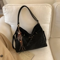 Detail of black suede tote bag with golden hardware and cute brown bear charm on a sofa - With Charm / Black