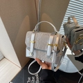 Zilvergrijze crossbodytas met textuur, gouden hardware en handvat op een spiegelend oppervlak - Zilver