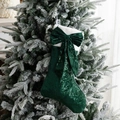 Sparkling dark green sequin Christmas stocking with bow and faux fur trim on a tree - Green