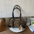 Dettaglio della borsa Boston leopardata con ciondolo da baseball su un tavolo di legno - Con Ciondolo da Baseball / Stampa leopardata