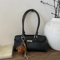 Detail der schwarzen Retro-Eimertasche mit goldenem Drehverschluss und braunem Bärenanhänger - Schwarz (mit Anhänger)