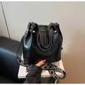 Détail d'un sac seau noir à motif crocodile avec bandoulière large et finitions dorées - Noir