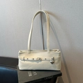 Minimalist beige leather shoulder bag with decorative straps and silver heart pendant - White