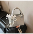 Detail of light gray lychee leather handbag with pearl charm and white ribbon bow - Gray